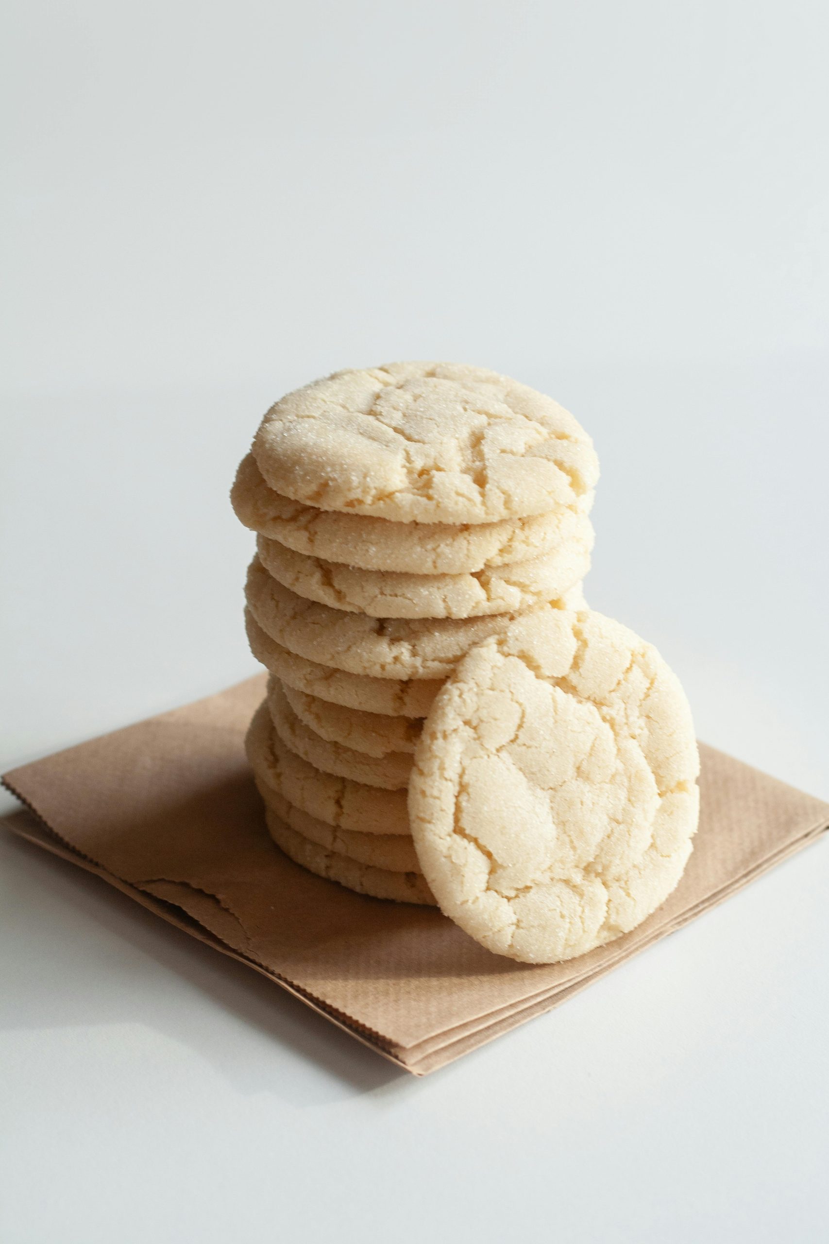 A stack of freshly baked homemade sugar cookies on a rustic paper surface, perfect for dessert lovers.
